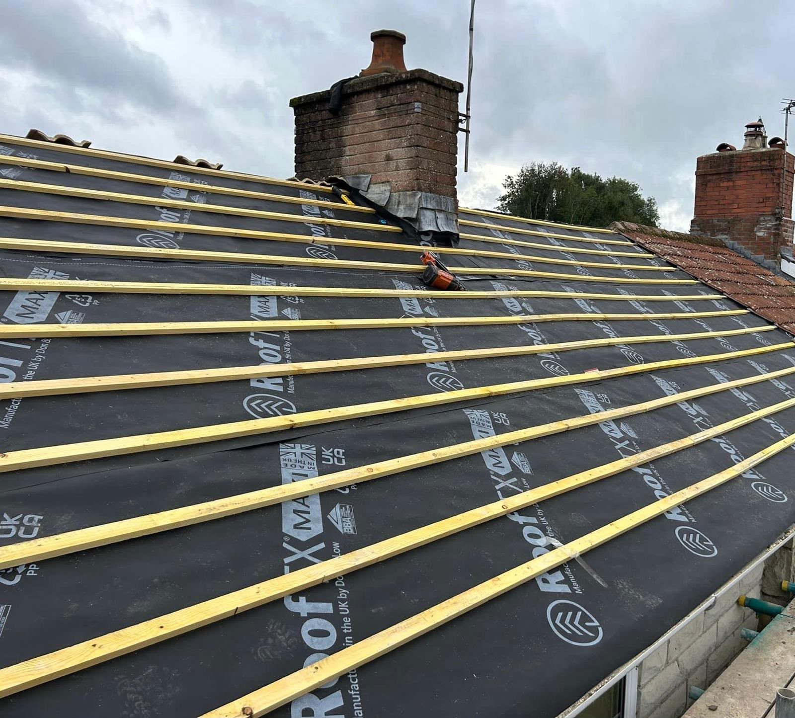New roofing membrane and timber battens fitted around a brick chimney during a re-roof