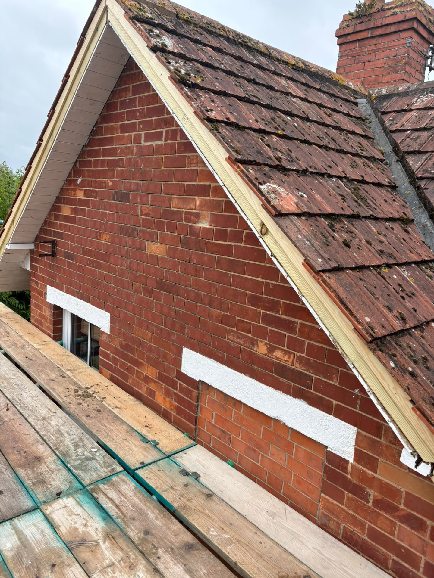 New timber bargeboard being fitted to a brick gable before new fascias, Glastonbury