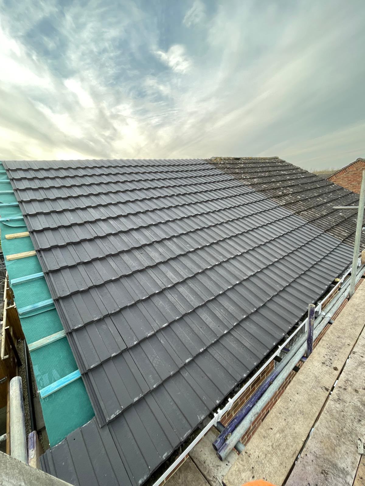 New dark grey tiles being laid alongside old weathered tiles, re-roof in progress, Somerset