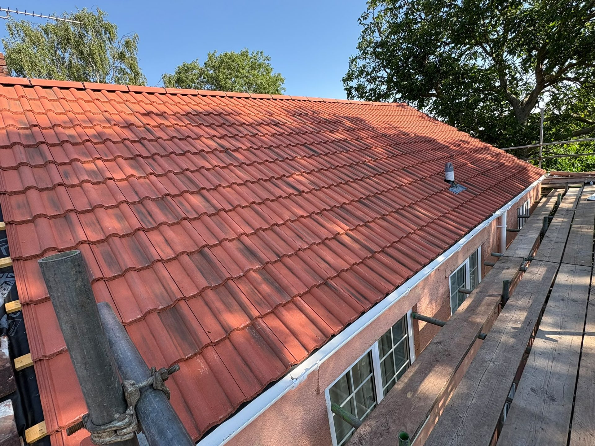 Newly re-tiled red concrete tile roof with white guttering, re-roofing in Glastonbury, Somerset