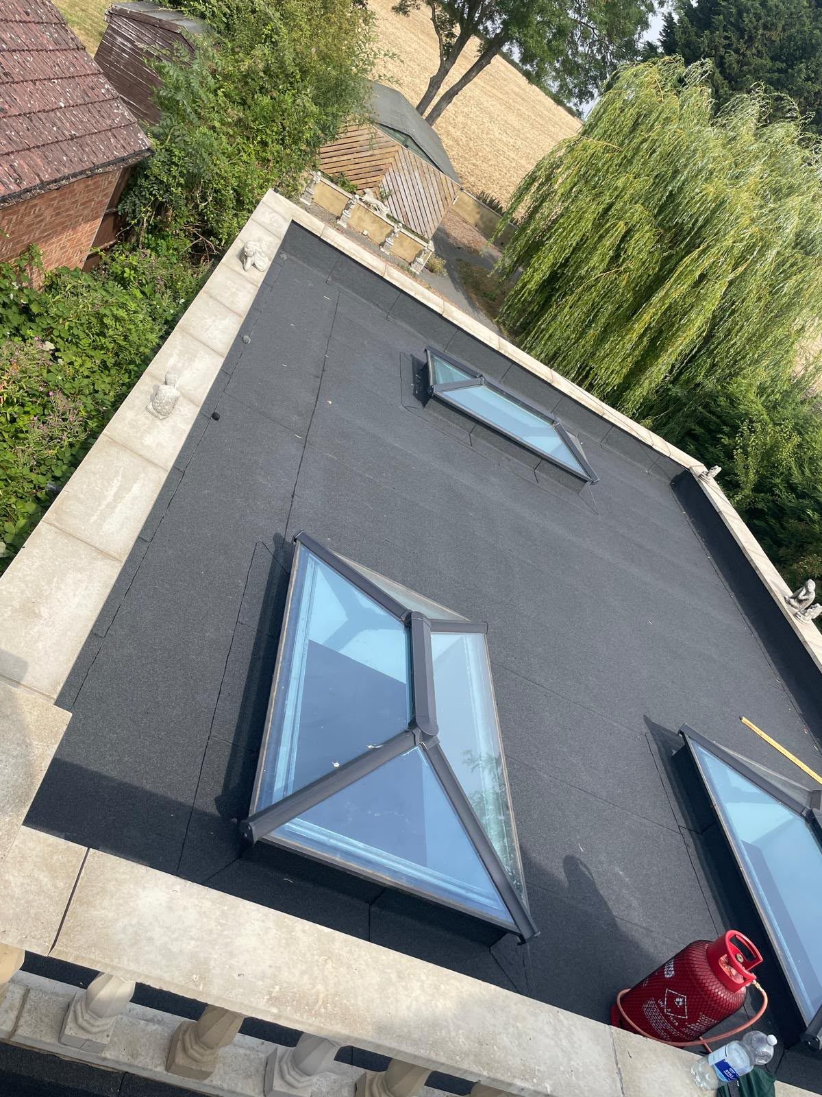 Newly felted flat roof with three roof lanterns behind a stone parapet, flat roofing in Somerset