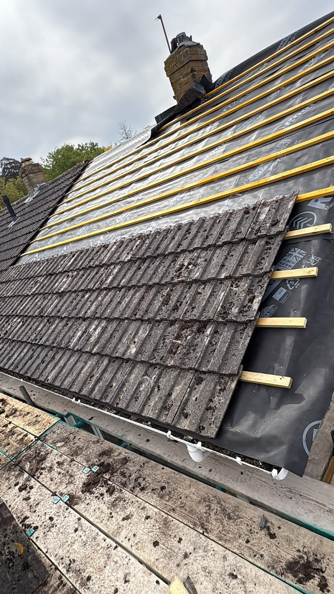 Old concrete tiles being stripped onto new membrane and battens, re-roofing in progress, Glastonbury