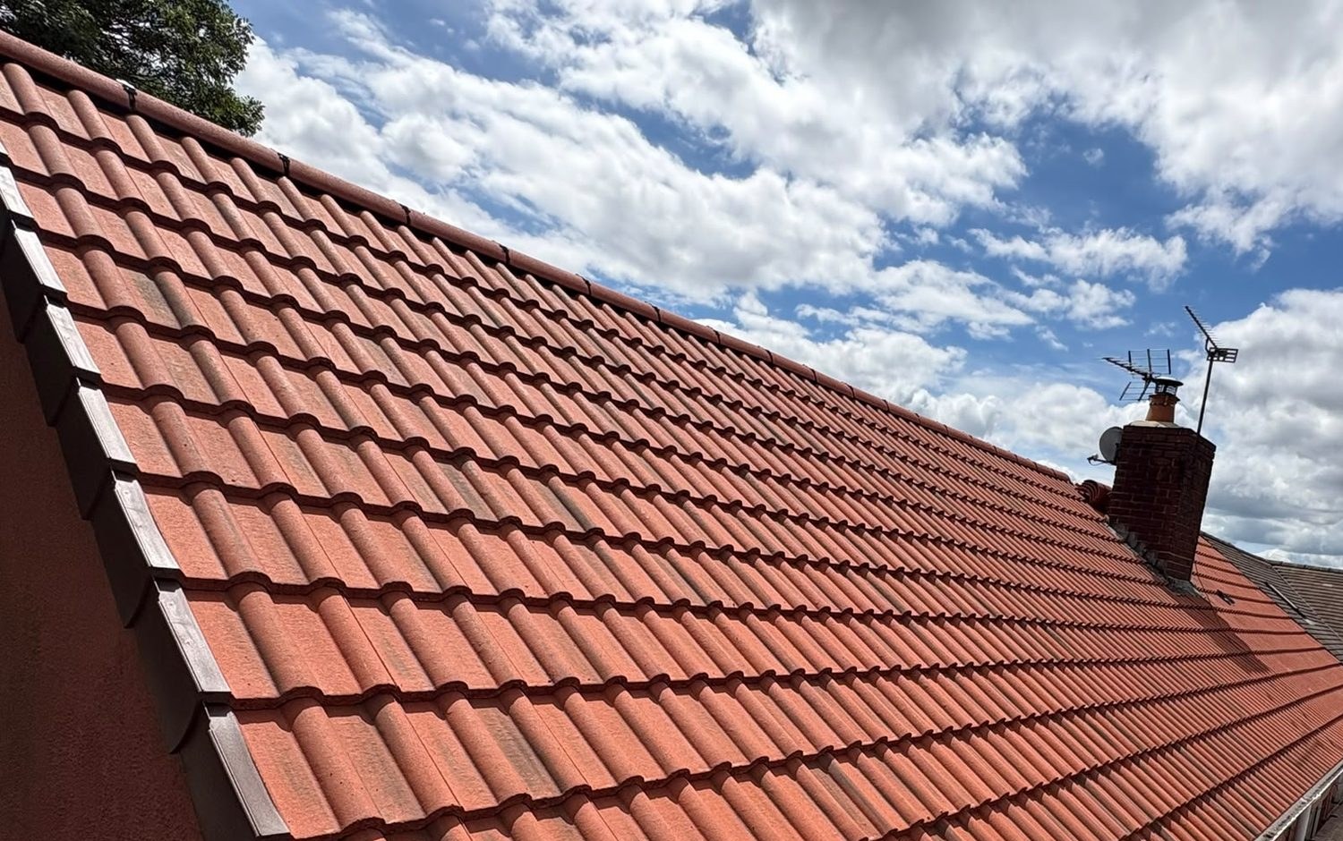 Red tiled pitched roof under a blue sky, roofer in Glastonbury, Somerset